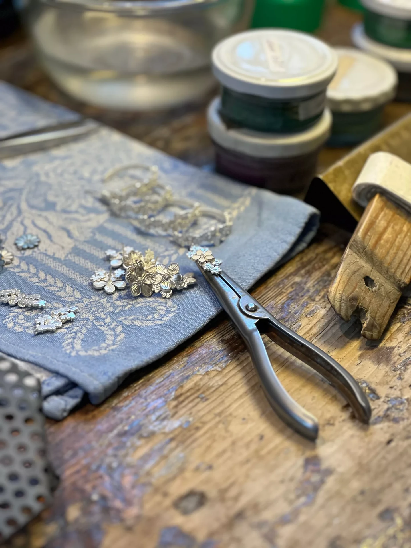 Silver and gold floral jewellery pieces resting on cloth at a David-Andersen goldsmith workbench